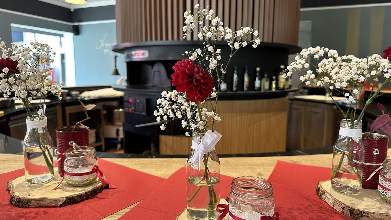 Blumendekoration auf der Theke vor dem runden Pizzaofen